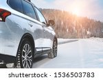 Modern Suv four wheel drive car stay on roadside of winter road. Family trip to ski resort concept. Winter or spring holidays adventure. car on winter snowy road in mountains in sunny day.