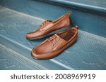 Brown leather boat shoes on a summertime blue fancy background.