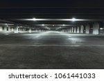 Grungy, dimly lit empty parking garage with overhead lights and an exit sign hanging from the ceiling.