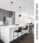 Small photo of OAK PARK, IL, USA - NOVEMBER 1, 2020: A modern, luxury grey kitchen with a white island looking out towards an open dining room and living room with hardwood floors throughout.