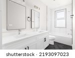 Small photo of A white luxury bathroom with a white vanity cabinet and marble countertop, subway tile shower, and dark hexagon tiled flooring.
