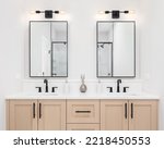A modern bathroom with a wooden vanity cabinet, black faucets, white marble countertop, and black rimmed square mirrors.