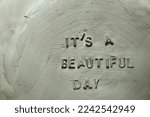 Small photo of The phrase It's a Beautiful Day written Stamping an inscription on a clay billet