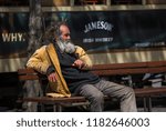 Small photo of Porto, Portugal - June 14 2018 - Old man with a long grey straggly beard sitting on a bench in front of a tram in the centre of Porto, Portugal