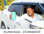 Small photo of Foucs on mobile, cab driver showing mobile phone with green screen mockup by looking at camera - concept of online booking servive, app advertising for travel service and promotions