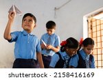 Small photo of teenage kid playing by throwing paper plane in classroom - concept of childhood lifestyle, development, mischief and learning