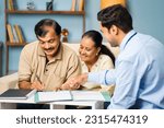 Small photo of Indian banker taking signature from senior man while with wife at home for documents - conept of financial advisor, realtor deal and satisfied customer