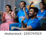 Side view shot of Group of family member shouting as India to support Indian Cricket Team while watching on tv at home - concept of Energetic fans, Cheering Family and Team Spirit.