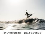 A silhouetted surfing airing on a wave breaking on a beach in puerto rico