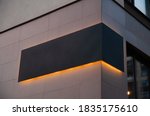 black advertising board with yellow led glow  on the corver of building, company sign on wall. Place for text