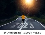 Man running on the mountain road towards new goals in 2023. New Year 2023 with new ambitions, challenge, plans, goals and visions. 
