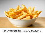 Salted French fries in white bowl on a wooden tray