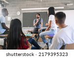Small photo of Teenager students listening and talking to friendly young male teacher - Group discussion in High School Education