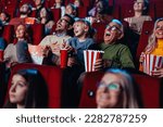 A grandfather and his granddaughter are in the movies enjoying themselves and having fun laughing out loud.