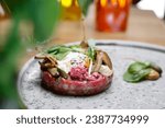 Small photo of Beef tartare, tartar steak with pickles, on a plate, close up, selective focus. Dish of raw ground beef meat.