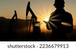 Silhouette of engineer with a digital tablet on the background of oil rigs