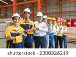 Small photo of Group of male and female factory labor stand smiling together with arms crossed in industry factory. Everyone wearing safety uniform and helmet. Workers working in the metal sheet factory.