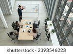 Small photo of An office setting show a group of people sitting around a table, seemingly involved in a serious business discussion.