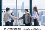 Small photo of Asian business team leader congratulate his teammate employee for the outstanding achievement team performance by shaking hand in the modern office workplace with skyscraper view