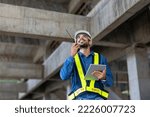 Small photo of Caucasian engineer with radio walkie talkie in full safety gear is inspecting inside the building structure for investigation over specification and quality control usage