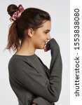 Small photo of Profile portrait photo of a dark-haired girl, posing on a white background. She's wearing dark grey sweatshirt. Her hair is pulled back with pink velvet scrunchie.