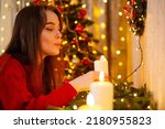Beautiful young girl, dreams and makes wishes at the candles in the New Year's Eve. Magical winter time, Christmas holidays