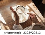 Small photo of Sieving flour for cooking tasty and airy bread. Girl using sieve for flour to make it airy for baking