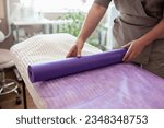 Small photo of Close up of beautician cosmetologist getting ready for a next visit of a client. Cosmetologist overspread her bed with violet disposable fiber for a next patient
