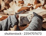 Man stacking firewood, prepares for cold winter, toned photo. Heating home with firewood in countryside during winter