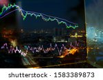 business financial chart or stock graph chart with ema and rsi indicators on laptop monitor, stock market graph in bear market and down trend and city night view on background