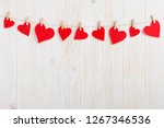 Red hearts on rope with clothespins, on a white wooden background. Place for text, copy space.
