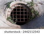 Small photo of A culvert under the highway with a metal grate at the entrance.