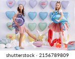 a cute little girls with balloons in the form of a heart in hands on many colorful heart balloons and big cake background. smiles,funny Valentine s Day birthday party