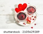 Hibiscus tea. The healthy hot organic drink is served in glass cups. St.Valentine's symbols as hearts, rose petals, and sweet sugar candies. Hard light, dark shadow, white wooden background, top view
