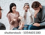 Small photo of Untuned parents try to reach out to little girl in headphones. Deficiency of attention in child. Family at consultation with family psychologist.