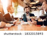 Small photo of People sit at a table eating sushi and drinking wine. The waiter brings sushi to business people who stipulate business ideas in a restaurant.