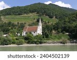 Small photo of Wachau, Lower Austria - 08 17 2023: The church of St. Johann im Mauerthale is pitoresquely located on the right bank of the Danube