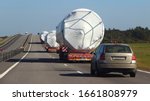 Oversize trucks convoy with escort car driving on suburban highway road at Sunny summer day, oversized logistisc business