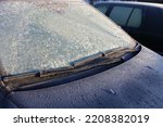 Frozen Car windscreen with wiper blade and hood on frosted windshield glass. Autumn morning frosts