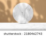Small photo of White Marble Table and Circle Marble Partition with Nature Shadow on Brave Ground Brown Concrete Wall Texture Background, Suitable for Cosmetic Product Presentation Backdrop, Display, and Mock up.