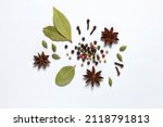 Assorted colorful spices peppercorns, bay leaf, cardamom, anise, clove on white background.