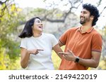 Happy indian couple laughing in the park, cheerful urban man and woman wearing casual t-shirt having fun together, friendship.