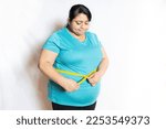 Small photo of Sad overweight indian woman check belly fat with measuring tape isolated over white background. Dieting and weight loose concept.