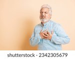 Small photo of Senior indian man wearing kurta suffering from chest pain isolated on studio beige background. heart attach, Copy space.
