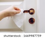 Close up view of woman hand using antibacterial wet wipe for disinfecting home room door link.