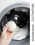 Small photo of Woman using wool dryer balls for more soft clothes while tumble drying in washing machine concept. Discharge static electricity and shorten drying time, save energy.