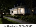 Small photo of Beautiful Colonial Revival style house with illuminated front porch at night in a suburban neighborhood