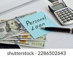 Small photo of Sheet of paper with the words Personal Loan on an office desk with a calculator, notepad, pen and US dollars