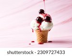 Small photo of Making vanilla ice cream scoop in a serve waffle cone with canned cherries and flowing cherry syrup on a pink background, copy space.