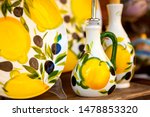 Small photo of Close up. Decoration items (plate, saucer, gravy boat, bottle for "aceto" (vinegar) with lemon, leaves, olives. Traditional Italian ceramics. Sirmione. Lombardy. Italy. Perfectly hand-painted pottery.